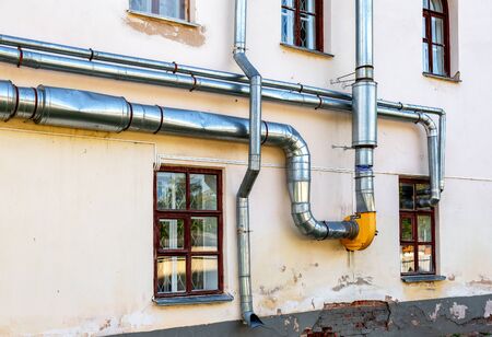 Metal pipes for ventilation and water mounted on the wall of buildingの写真素材