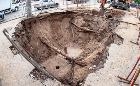 Construction works on rusty iron pipes at a depth of excavated trench. Replacement of heating pipes...