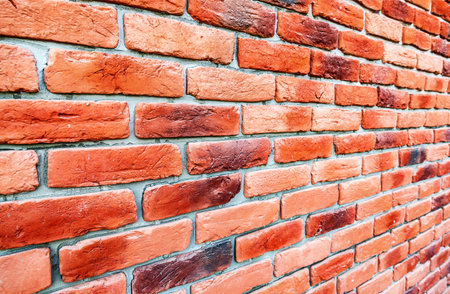 Old weathered red brick wall as background. Bricks masonry with seams. View from the angle