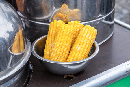 Steamed corn in a cooking saucepan, street food. Boiled corn cobs with a bit of sugar or salt to get...