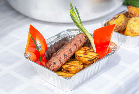Street food. Grilled sausage with potatoes, red peppers and onionsの写真素材