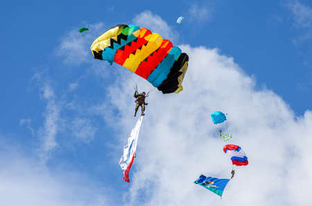 Samara, Russia - Septembers 11, 2016: Military parachute jumpers on a wing parachutes execute a controlled descent by parachute hung with airborne flagsのeditorial素材