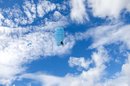 Parachute jumpers on a blue wing parachute on a blue sky backgroundの写真素材