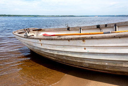 Wooden fishing boat on sandy bank of the river in summer dayの写真素材