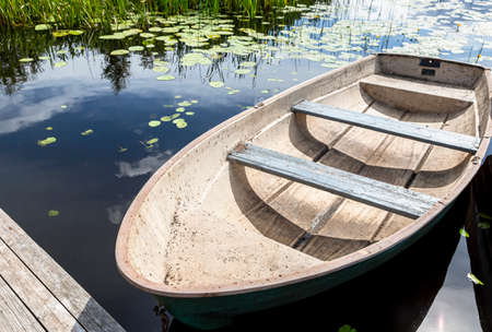 Old plastic fishing boat on the bank of the lake in summertimeの写真素材