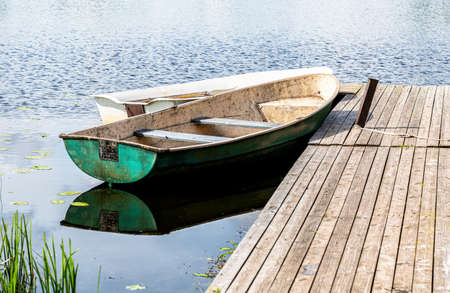 Old plastic fishing boats on the bank of the lake in summer sunny dayの写真素材
