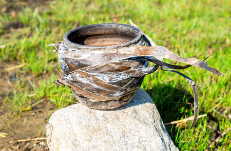 Antique handmade ceramic clay pot entangled in birch bark, closeup