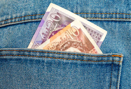 England pounds banknotes sticking out of the blue jeans pocketの写真素材