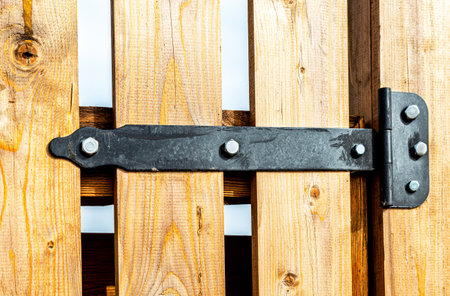 Black metal door hinge screwed to a wooden door