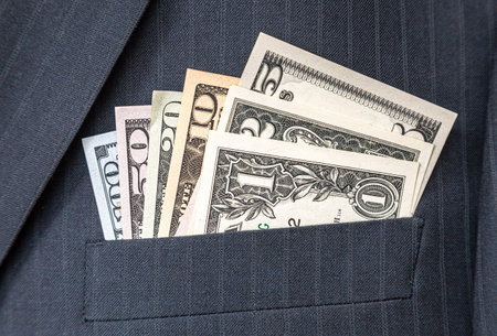 Various American dollar banknotes in businessman suit pocket. Money in the pocket of business suit