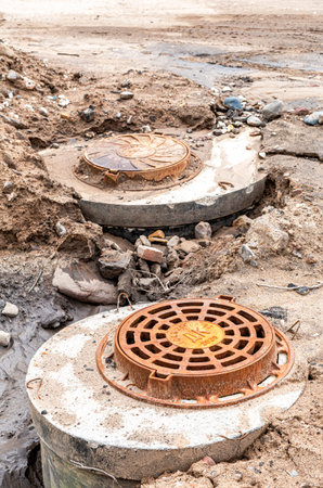 Borovichi, Russia - August 10, 2021: Rusty metal manhole cover on construction urban road. Round...