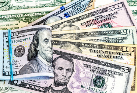 Folded american dollars banknotes wrapped by rubber band over dollars banknotes close up. business...