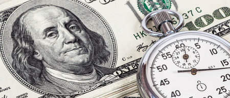 US dollar banknotes and stopwatch. Concept of time and money. selective focus