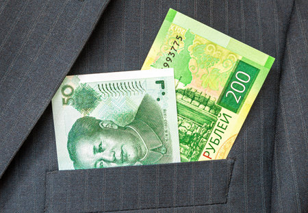 Russian rubles and Chinese yuan in businessman suit pocket. Money in the pocket of business suit....
