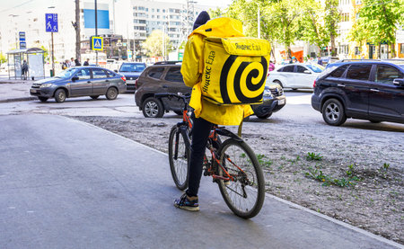 Samara, Russia - May 26, 2022: Courier of Yandex food delivery service on bicycles at the city street. Text in english: Yandex mealのeditorial素材