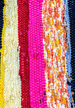 Background as handmade doormat from strips of cloth. Texture of a homespun rug from different...