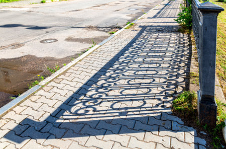 Shadow from the city decorative grating on the pavement. Rhythm and pattern of shadows in cityの写真素材