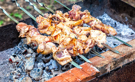 Cooking traditional appetizing hot shish kebab or shashlik on metal skewersの写真素材