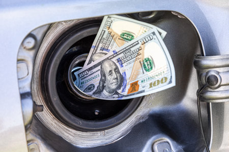 American dollars banknotes in the gas tank of a vehicle. Concept photo of the rising fuel price. fuel economyの写真素材