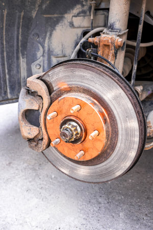 An old rusty car brake disc is lubricated with copper grease before installing a car wheelの写真素材