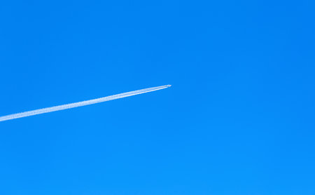 Passenger plane flies high in the blue sky. Trace of the plane in the skyの写真素材