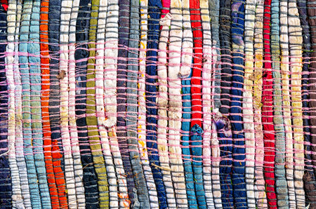 Old homespun doormat made from strips of cloth as background. Handmade texture of a rug from...