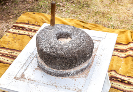Ancient stone rotary mill for hand-grinding a grain into flour. Old hand-driven mill grinding wheat