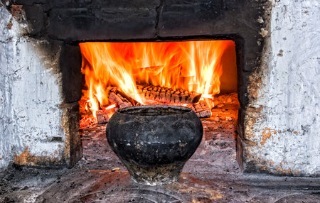 Brick oven with cast iron pot and burning firewood at the village house, close upの写真素材