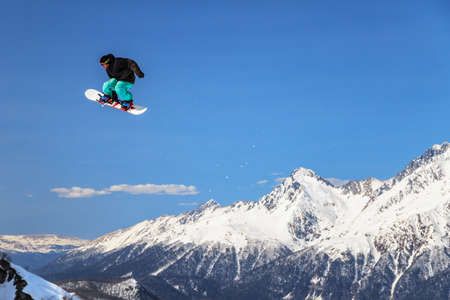 Sochi, Russia - March 25, 2014: Quiksilver New Star Camp is the most large-scale sports and entertainment mountain camp for ski and snowboard riders in Russia. A male snowboarder is flying from a jumpのeditorial素材