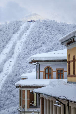 Hotel roofs of Gorky Gorod winter mountain resort covered with snow with cableway lift on the background vertical scenic landscapeの写真素材