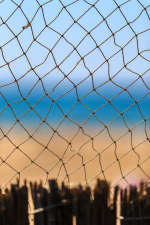Fishing net at summer seaside on blue sky and sandy beach scenic background. Beautiful vertical maritime viewの写真素材