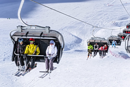 Sochi, Russia - January 20, 2013: Skiers and snowboarders ride on chair ski lift on sunny winter day...