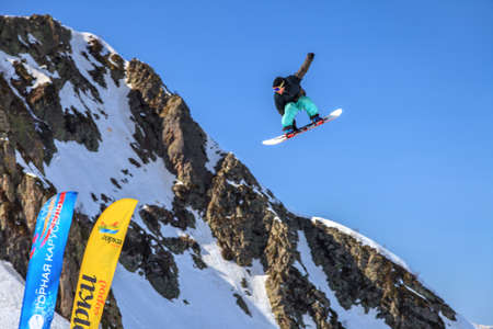 Sochi, Russia - March 25, 2014: Snowboarder flies in air from Big Air jump on blue sky and mountain backgroundのeditorial素材