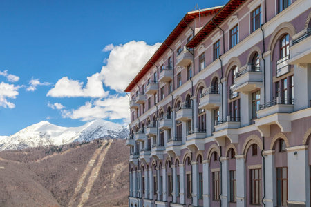 Sochi, Russia - Aprel 10, 2014: Modern Rixos Sochi Krasnaya Polyana hotel building in Gorky Gorod mountain ski resort fronts on snowy mountain peaks blue sky scenery. Scenic view on sunny day at springのeditorial素材