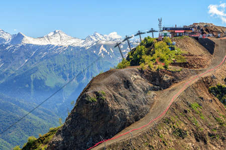 Beautiful scenic summer landscape of Caucasus mountain peaks with snow tops at Gorky Gorod mountain ski resort in Sochi, Russia on sunny day under clear blue sky. Ski slope and ski lift station viewのeditorial素材