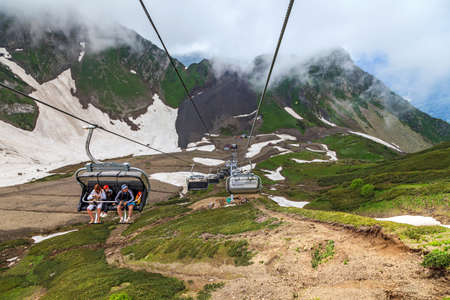 Sochi, Russia - June 9, 2014: Family rides on cable way chair ski lift in Gorky Gorod mountain resort at spring. Caucasus mountains. Aibga ridge cirque. Scenic landscapeのeditorial素材
