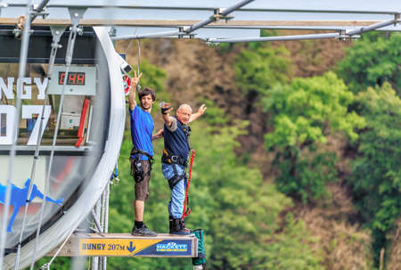 Sochi, Russia - June 7, 2015: Old man with  camera on wrist is about to jump 207 meter bungy at AJ Hackett Sky Park on mountain forest background. Extreme activities of Sochi mountain resortのeditorial素材