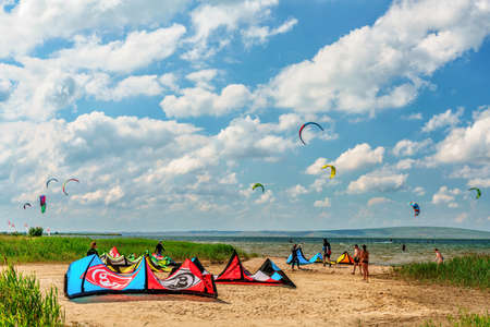 Anapa, Russia - June 11, 2017: Colorful kites rest on firth shore sand at Black Sea Blaga Beach resort on sunny day on distant flying kites background with clouds. Popular summer kitesurf destinationのeditorial素材