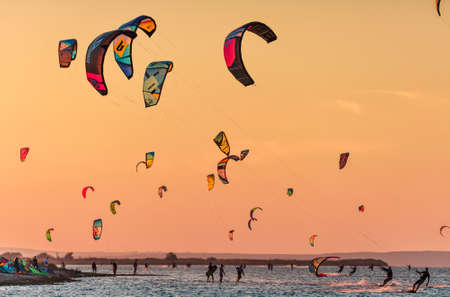 Anapa, Russia - Sebtember 9, 2017: Kitesurfer ride kites on flat surface of Bugaz firth at Black Sea Blaga Beach resort at sunset. Popular kitesurf and windsurf destination. Sunny summer scenery.のeditorial素材