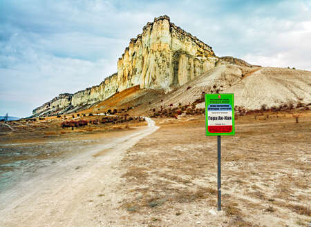 Crimea, Russia - October 11, 2019: Scenic landscape of Belaya Rock Ak-Kaya with information sign on foreground. Mountain peak by Belogorsk. Popular tourist destination..のeditorial素材