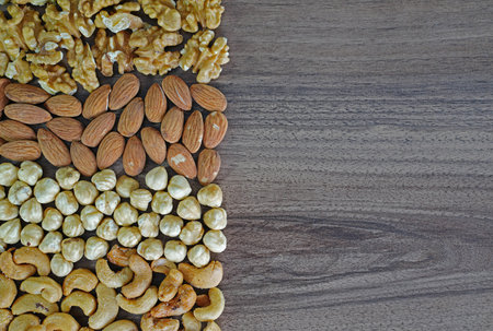 Nuts background, walnut, almond, hazelnut and cashew nuts in order on wooden tableの写真素材
