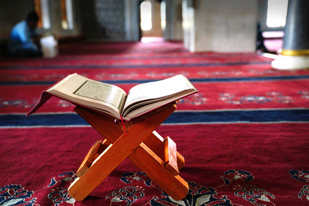 Holy Koran on stand on red carpet and blurred interior of a mosque in backgroundの写真素材