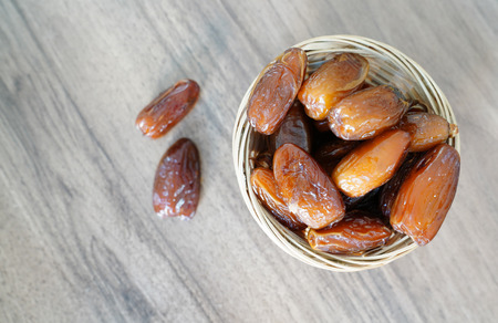 Fresh fruit dates in a basket bowl on walnut wooden tableの写真素材