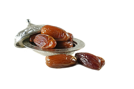 Fresh fruit dates in a silver metal bowl on isolated white backgroundの写真素材
