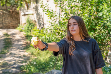 Cukuroren, Bilecik / Turkey -September 08 2019: Portrait of a girl holding at a half eaten apple and green tree in backgroundのeditorial素材