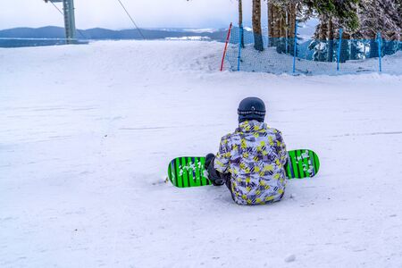 Back view of snowboarder sitting and relaxingの写真素材