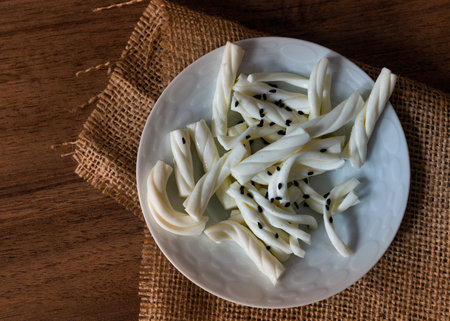 White braided cheese with black sesame served in a white plate