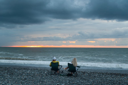 Silhouette of rear view of couple sitting beautiful sunset in Batumi, Georgia.