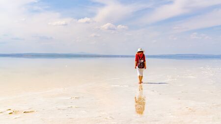 Silhouette of woman wearing red shirt and white hat walking on the famous tourist destination Salt Lake (Turkish: Tuz Golu ) is the second largest lake in Turkey.の写真素材