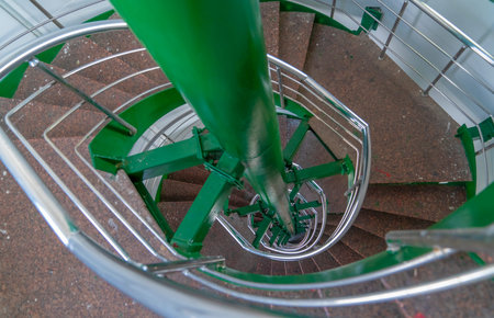 Spiral multi-flight stairway with metal handrails seen from the top of the staircase